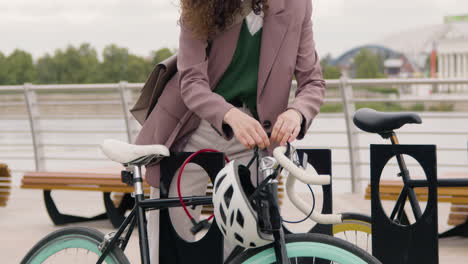 cerca de una mujer irreconocible con ropa formal estacionando su bicicleta en el puente de la ciudad mientras iba a trabajar