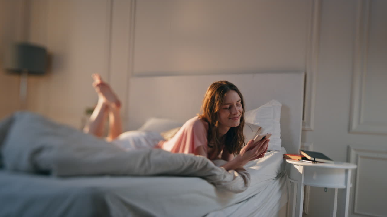 아침 소녀는 빛 아래에서 드폰으로 이야기하고 있습니다. 편안하고 매력적인 여성은 어 놓습니다.