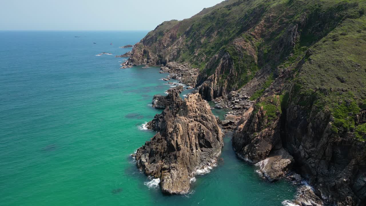 Stunning slow motion rotating drone shot over stone cliffs next to ocean