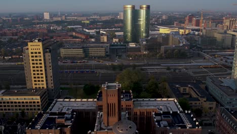 train tracks behind exterior facade of inktpot building with ufo resting on it at sunrise with central train station and shiny architecture of utrecht in the background