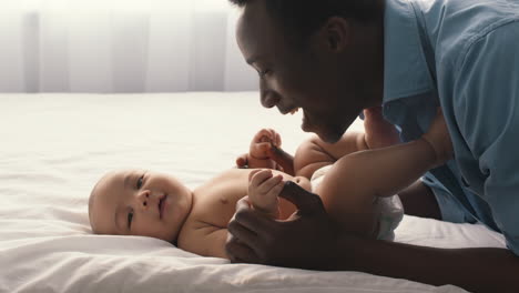 a father affectionately interacting with his baby on a bed