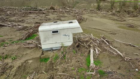 pickup mobile capsule stranded on muddy ground with broken trees, aftermath cyclone