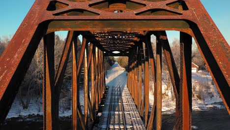 aerial crane up close up of a rusty railroad trestle on a cold winter morning revealing a truck crossing the tracks in the distance