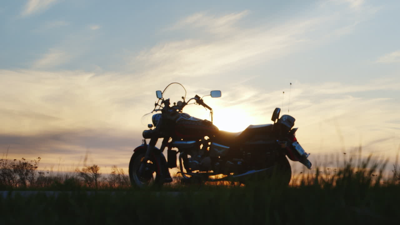 그의 오토바이에가는 일몰에 자전거 타는 사람의 실루엣