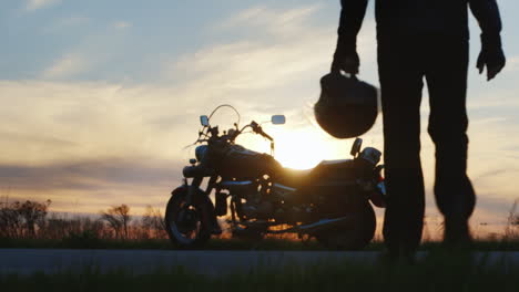 silhouette of biker at sunset that goes to his motorcycle