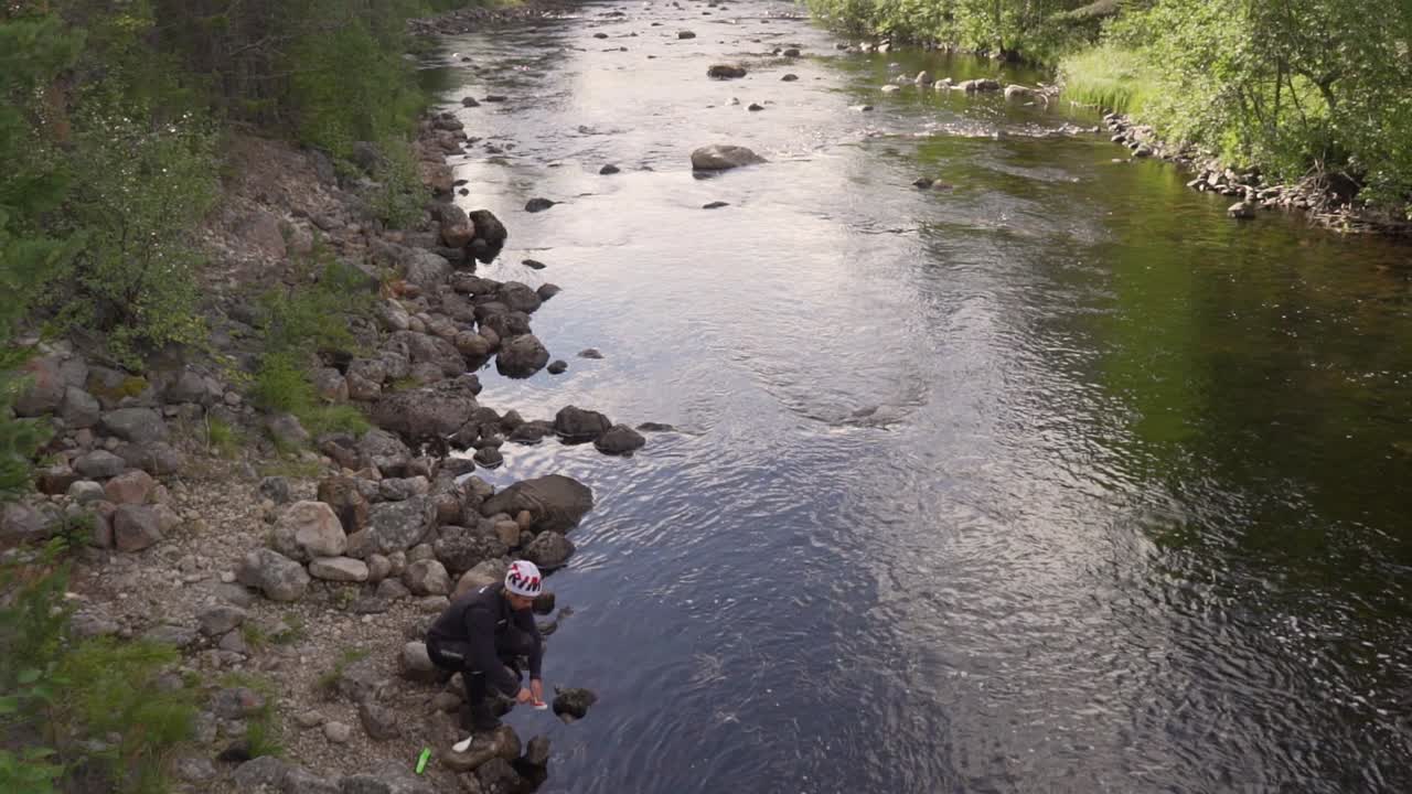 un hombre está lavando los platos en un río