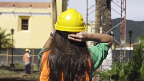 female engineer putting a construction helmet on a working field