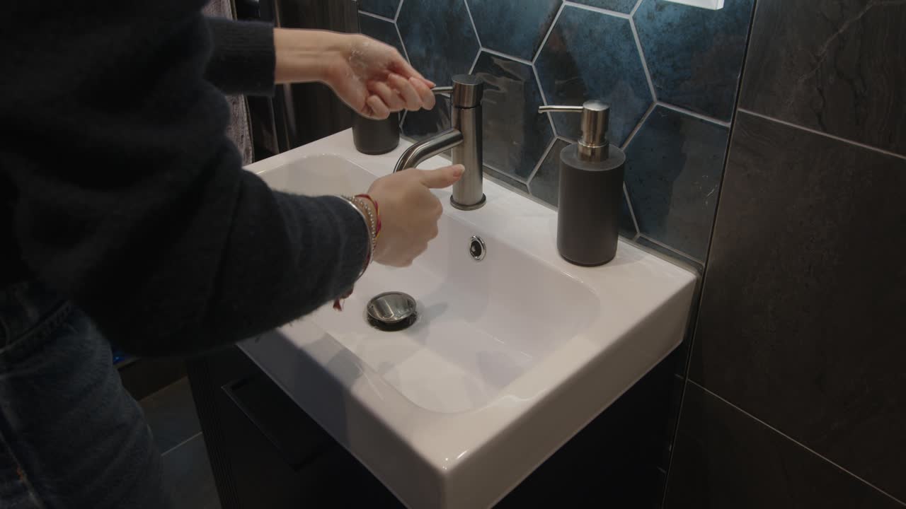 modelo femenino lavándose las manos en un lavabo de baño moderno
