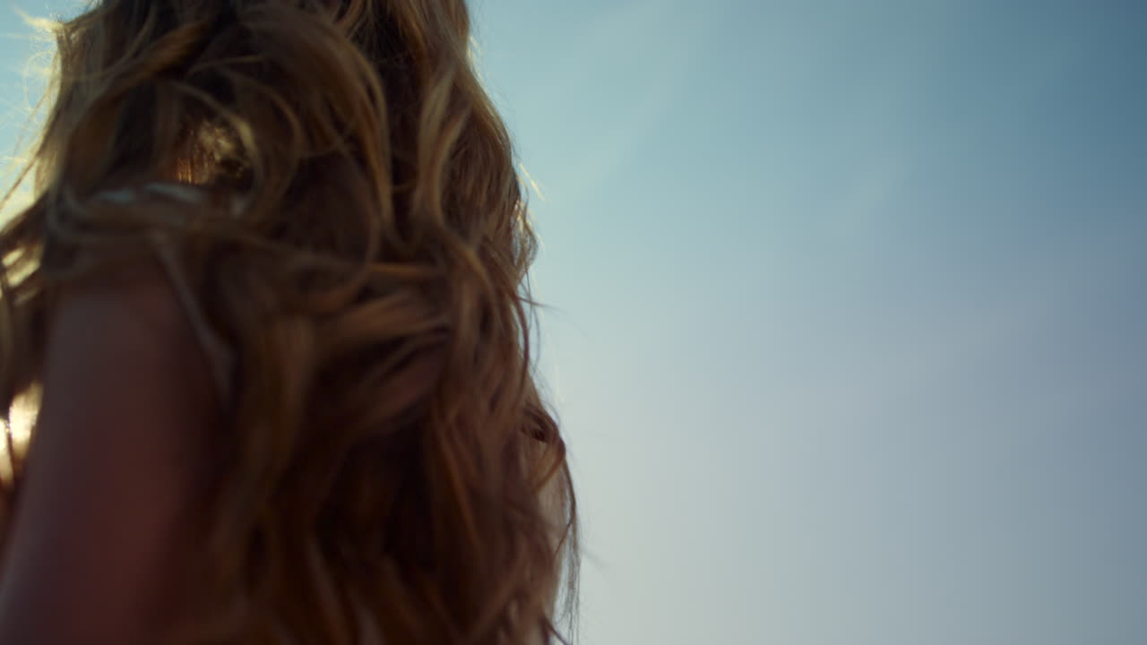 Giovane donna con bei capelli in piedi contro la luce del sole. Concetto religioso.