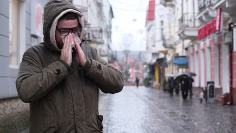 a european man in glasses has caught a cold coughs in the middle of the street in the rain a european man in glasses has caught a cold coughs in the middle of the street in the rain unhealthy guy with flu symptoms pandemic concept video