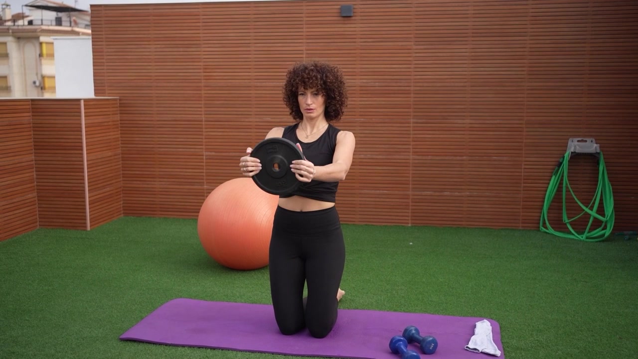 A woman practices yoga outdoors on a mat focusing on her balance and breathing