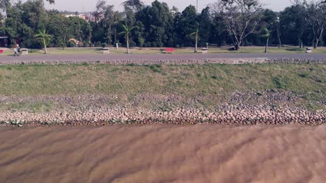 view of the muddy water waves of the sukhna lake on a windy day near the pedestrian lane in chandigarh