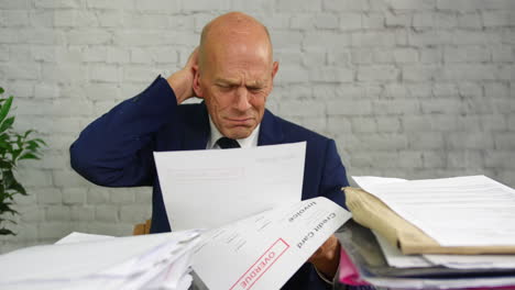 a depressed crying man opening a stack of bills and letters with final notice for credit card debts