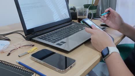 close-up of hands using a tablet with documents, alongside a laptop