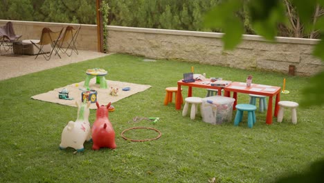 colorful outdoor play area for children featuring toys, tables, and chairs set on a grassy lawn, creating a playful and inviting environment