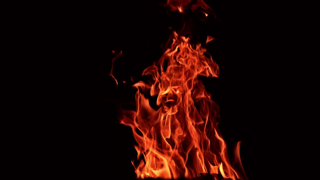 Pieces of wood burning in a big campfire. Large tongues of flame rising up in the darkness.
