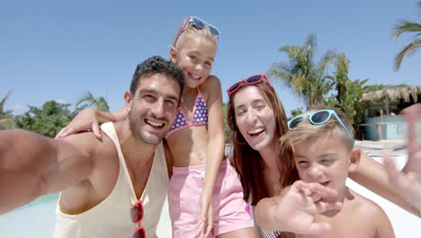 retrato de una feliz familia caucásica tomando selfies y agitando las manos en la casa de la playa