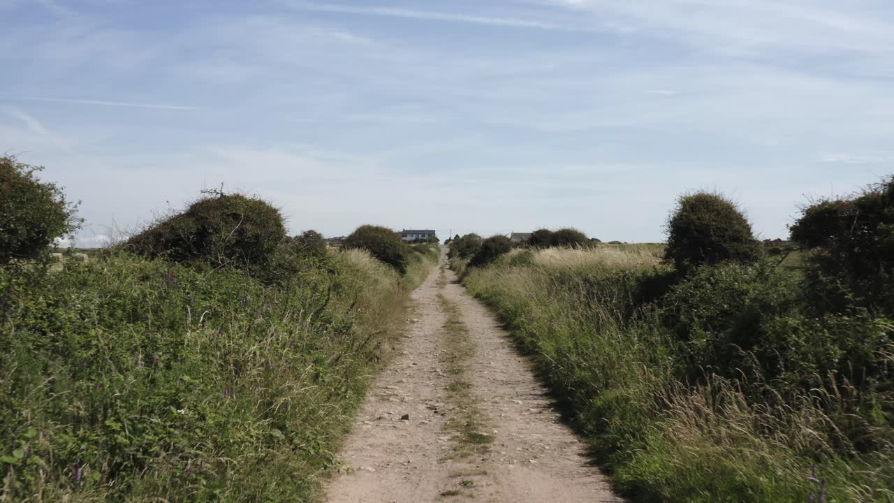 pov: camino de tierra agrícola conduce a la antigua casa de campo en medio de campos de cultivo