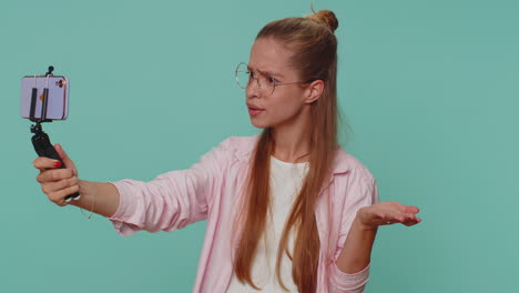 blogger impresionada tomando una selfie en el teléfono móvil selfie stick, comunicándose por video llamada en línea
