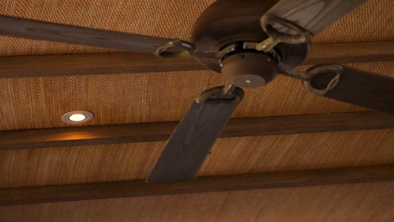A ceiling fan rotates steadily in a warmly lit wooden room, creating a calming atmosphere