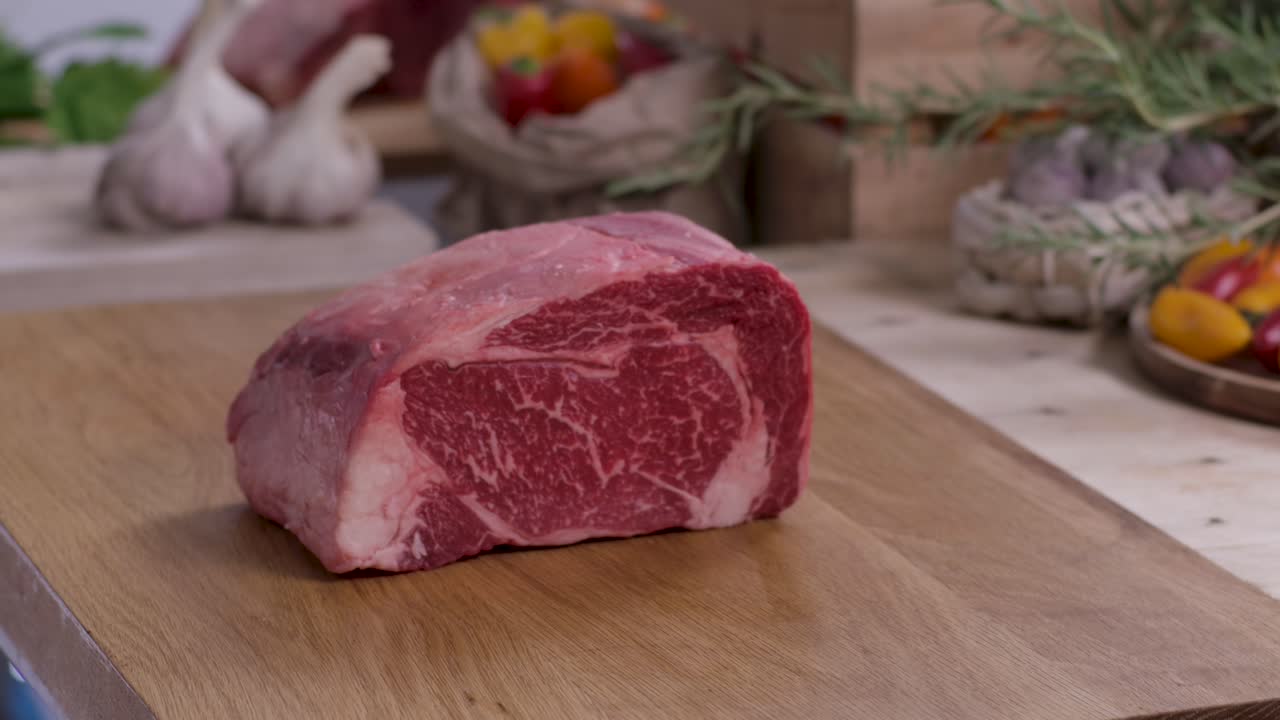 Close up of a butcher placing a large, prime marbled beef ribeye roast onto a wooden cutting board, ideal for high-protein bodybuilding meal prep content