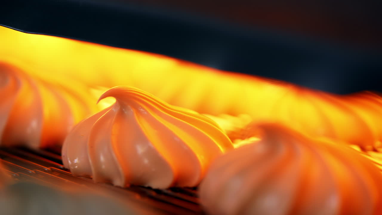 Marshmallow candies go under the drier on conveyor grid. Close up. Automated manufacturing of sweets at modern factory.