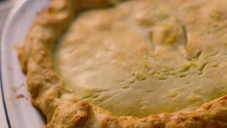 moving top down view of homemade deep filled shortcrust chicken mushroom vegetable pie with golden crimped pastry ready to eat. comforting british tasty delicious food.