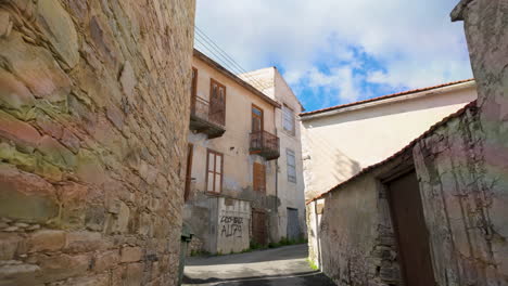 Schmale-Dorfgasse-Zwischen-Alten-Steinmauern,-Die-Zu-Traditionellen-Gebäuden-Unter-Klarem-Himmel-Führt,-Ein-Hinweis-Auf-Den-Rustikalen-Charme-Von-Lefkara