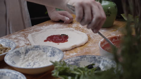 Nahaufnahme-Der-Hände-Des-Küchenchefs,-Der-Die-Pizzasauce-über-Den-Teig-Verteilt