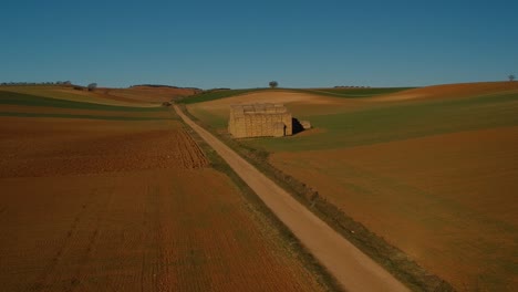 aerial shot moving towards a big block of stacked straw bales at the side of a road
