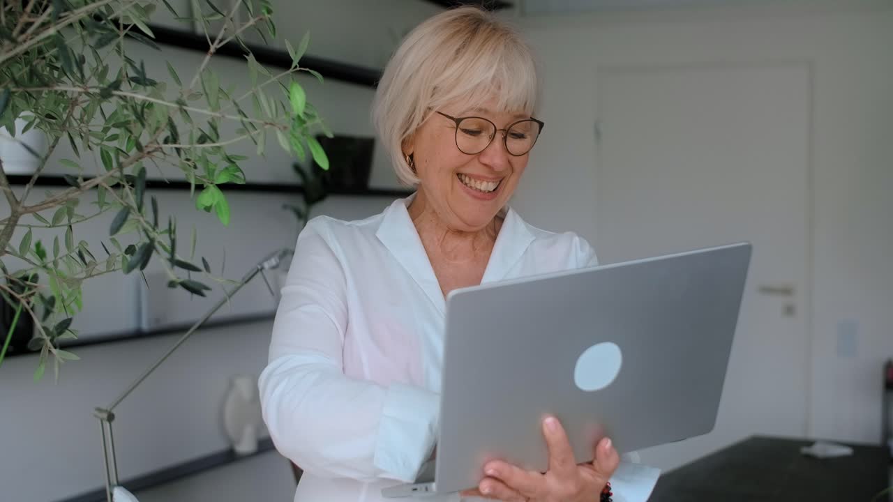mujer mayor trabajando en una computadora portátil en casa