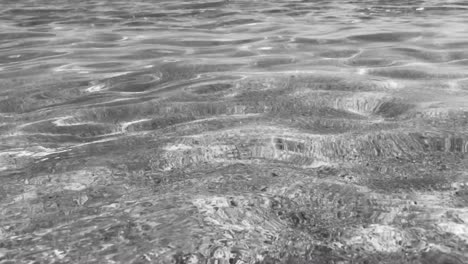 black and white sea ripples in 4k of pure crystal clear water with sandy sea floor