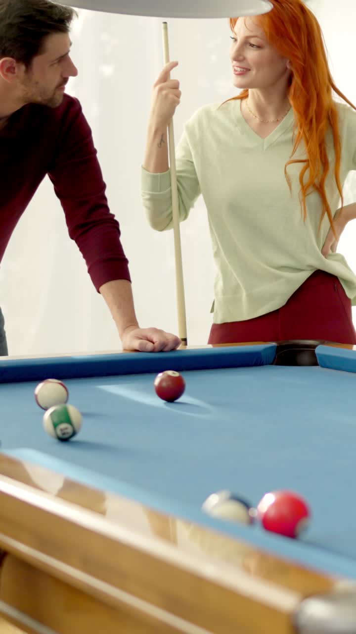 Women flirting with man while playing pool at home