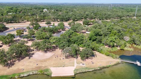 pulling back from a large grove of oak trees at a state park with picnic benches and a playground