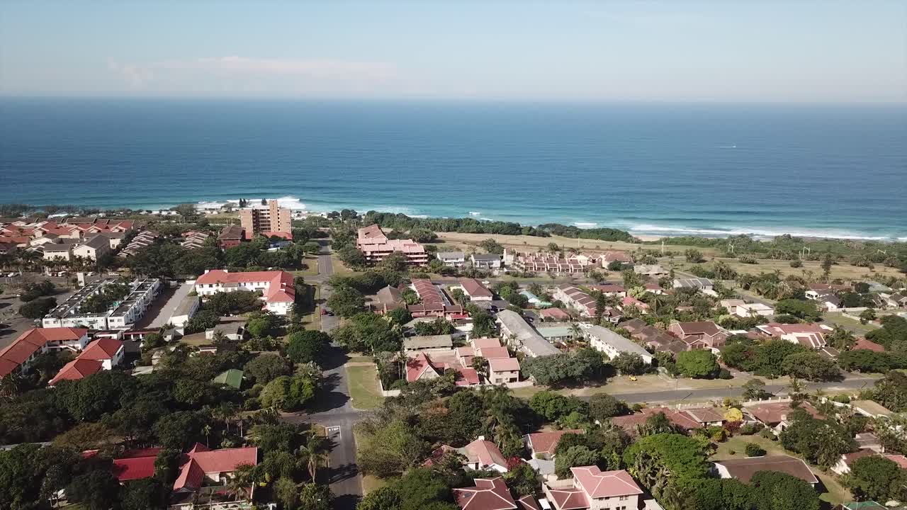 imágenes aéreas filmadas por un dron de la playa de scottburgh y campos de hierba con casas residenciales con vista al mar en kwa zulu natal sudáfrica