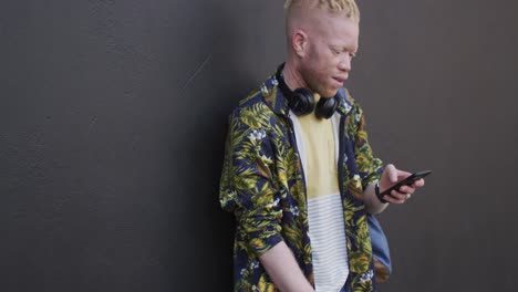thoughtful albino african american man with dreadlocks using smartphone