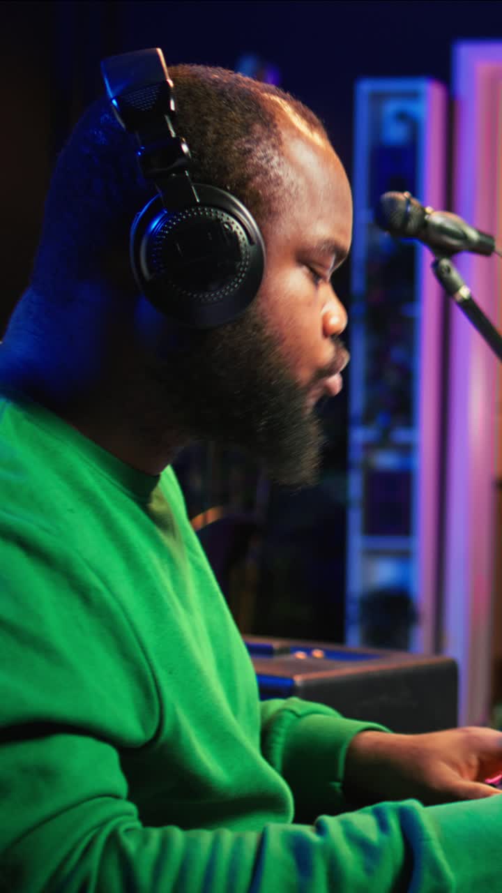 Afroamerikansk mand producerer musik med hovedtelefoner i studie