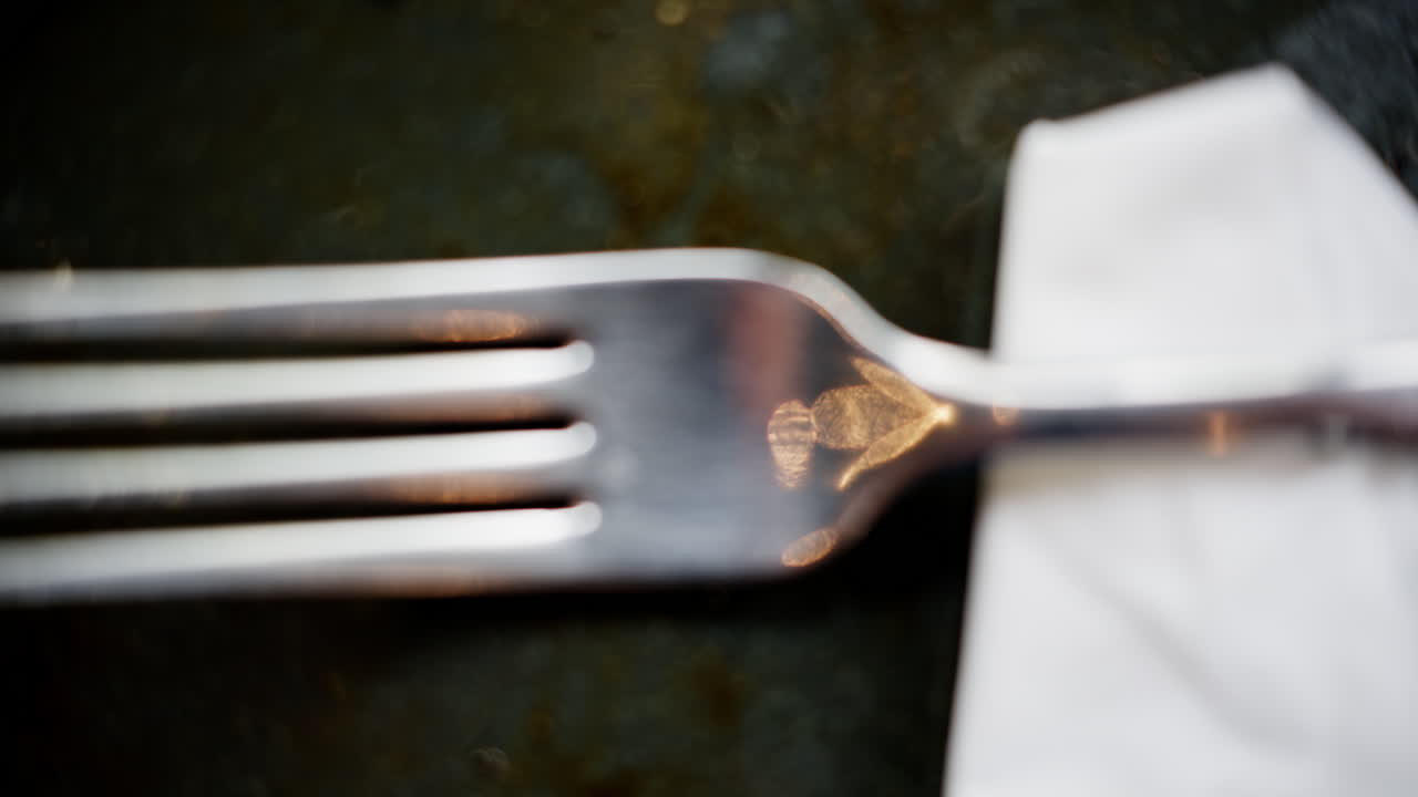 Close up of a steel fork on a paper towel and a black plate