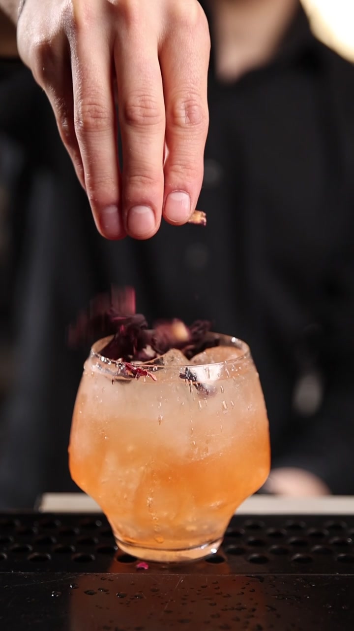 Barman che guarnisce un cocktail con petali di ibisco essiccati