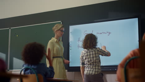 teacher using interactive digital whiteboard. student writing on smart board