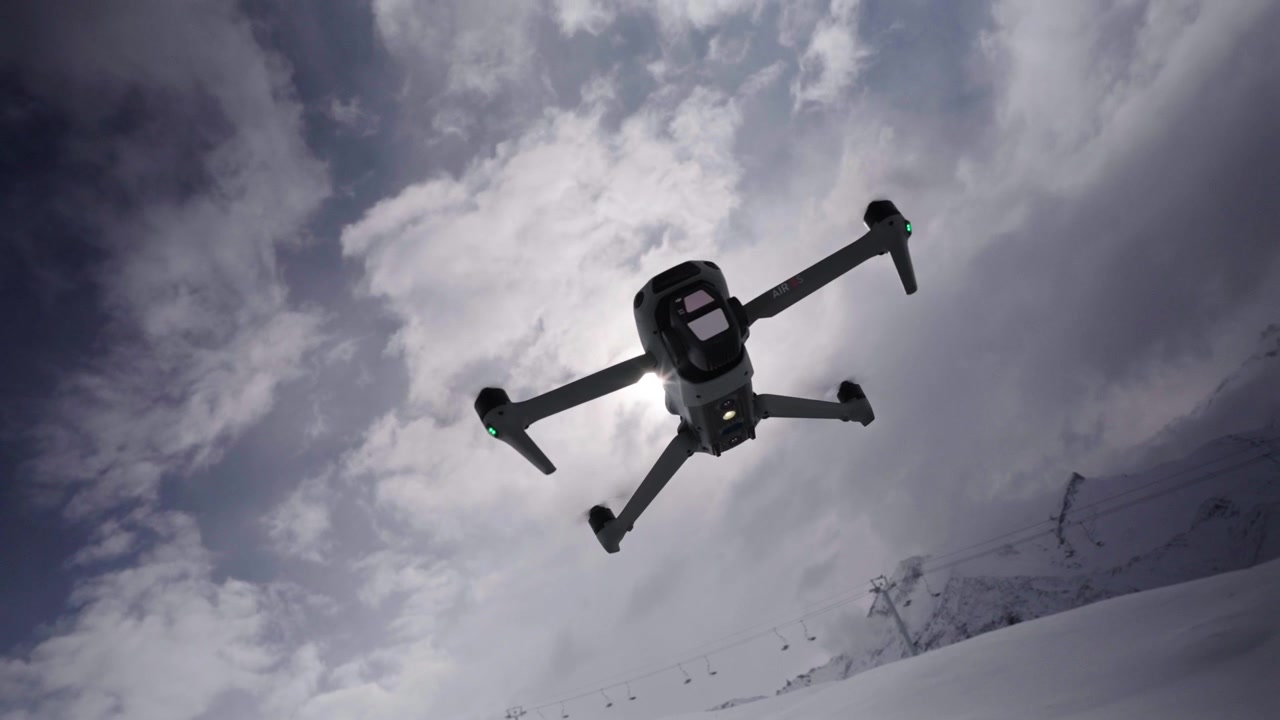 Drone svæver i luften over et stort, uberørt snedækket landskab i Argentina, set fra lav vinkel med barske bjerge, stemningsfulde skyer, diffust sollys og sprød vinteratmosfære. Perfekte luftoptagelser.