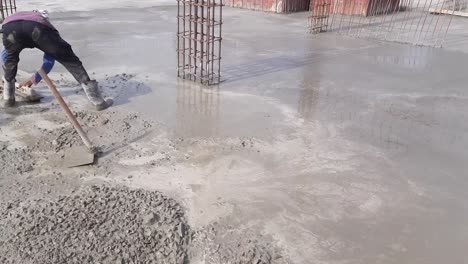 a worker leveling pcc foundation concrete slab on a new building construction site