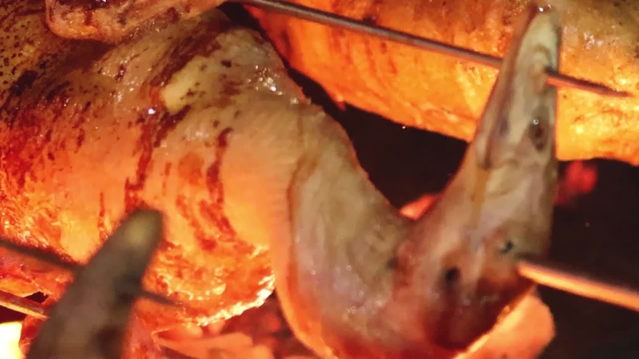 Detailed view of a duck turning on a rotisserie, showcasing its crispy, golden skin.