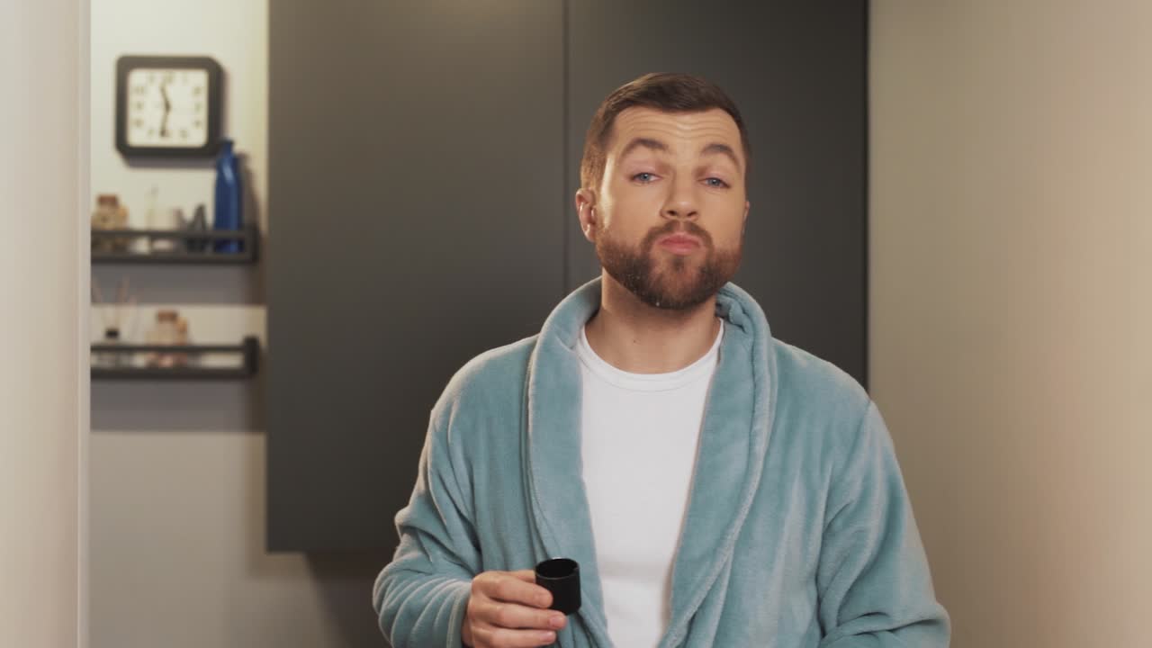 목욕 가운을 입은 잘 생긴 남자가 특산품을 입에 넣었다