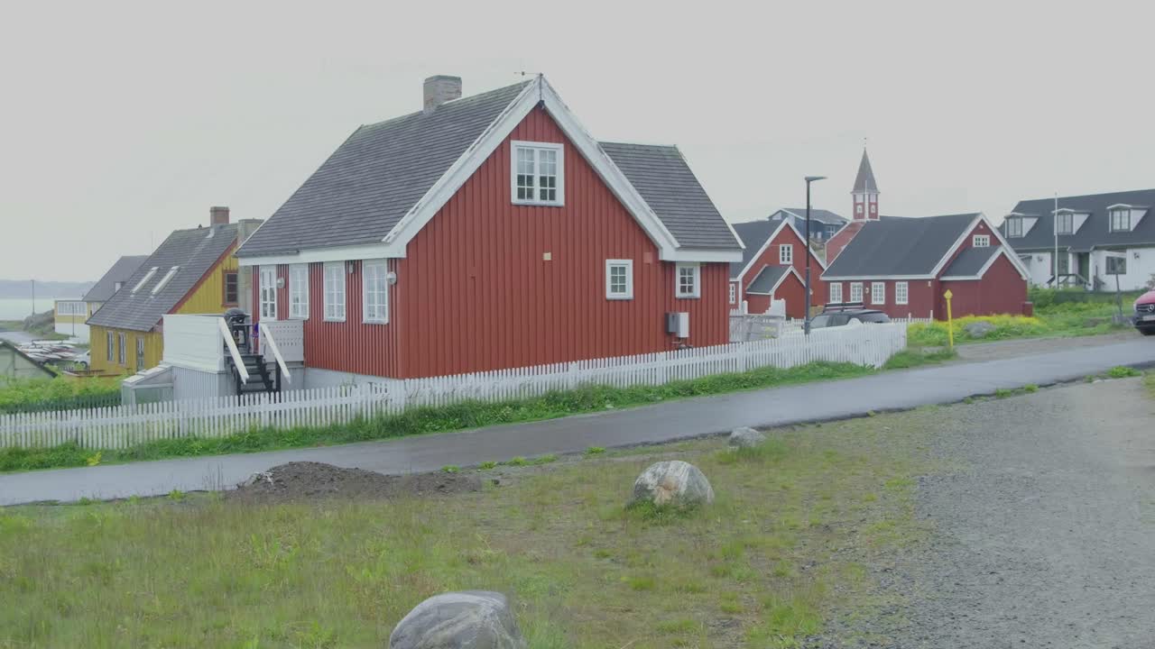 Nuuk, Grønland 2025: Bygader med grønlandsk flag og hvide stakitter.