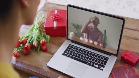 Biracial-man-with-wine-making-valentine's-day-video-call-on-laptop