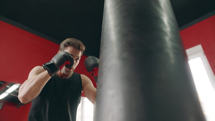 Uomo kickboxer che sferra colpi durante l'allenamento di combattimento. Sportivo che fa allenamento cardio.