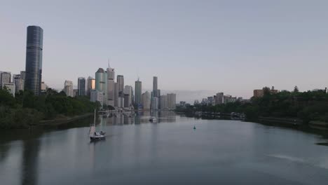 cinematic drone flying low over river towards brisbane city at sunrise