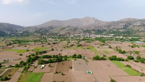 Aerial-forward-of-rural-area-and-cultivated-fields,-Spinalonga