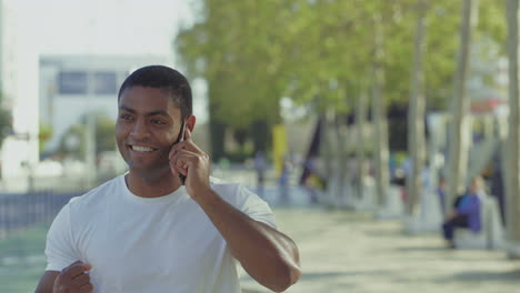 successful sportsman talking on smartphone outdoor.